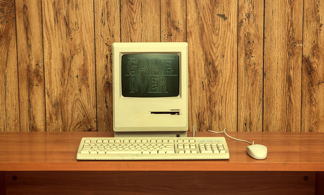 Vintage 1990s Apple Mac computer with 'Game Over' on the screen in green retro lettering