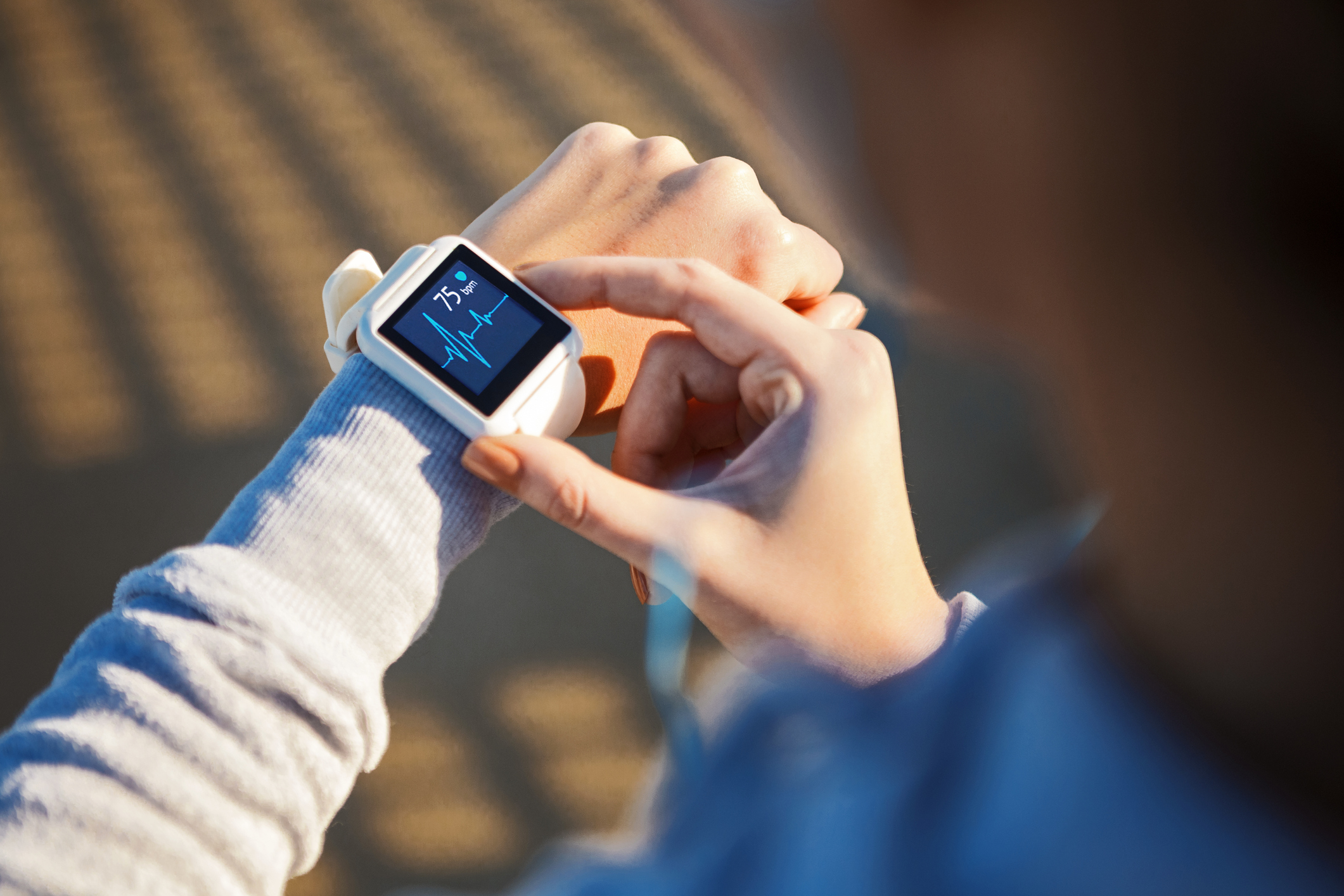 A woman checks her heart rate on a wearable watch app; it says 75 bpm