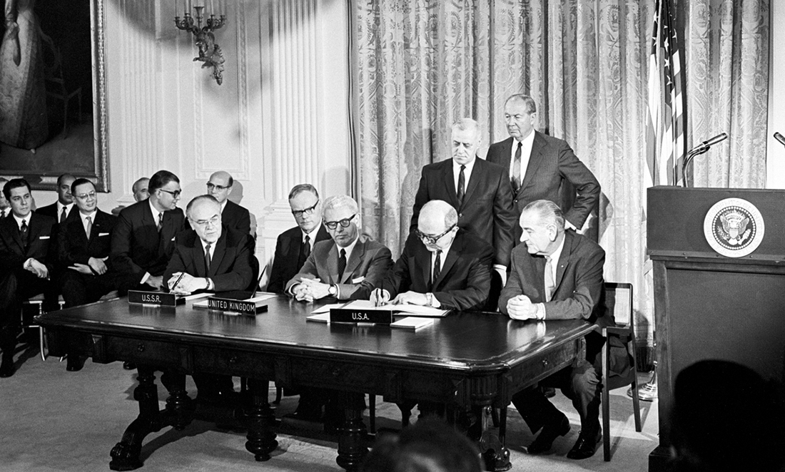 Eight men sit around a table to sign the Outer Space Treaty in 1967
