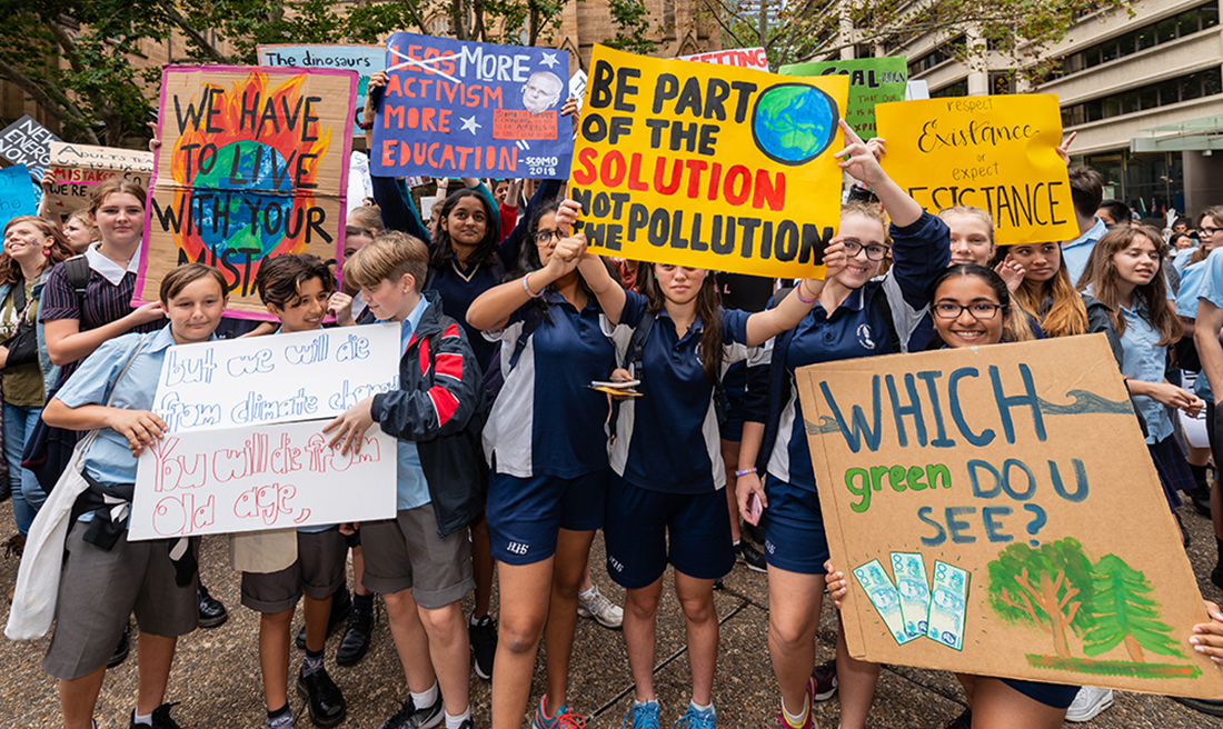 Group of school aged students holding banners at a Climate Strike - one reads 'Be part of the solution, not the pollution'