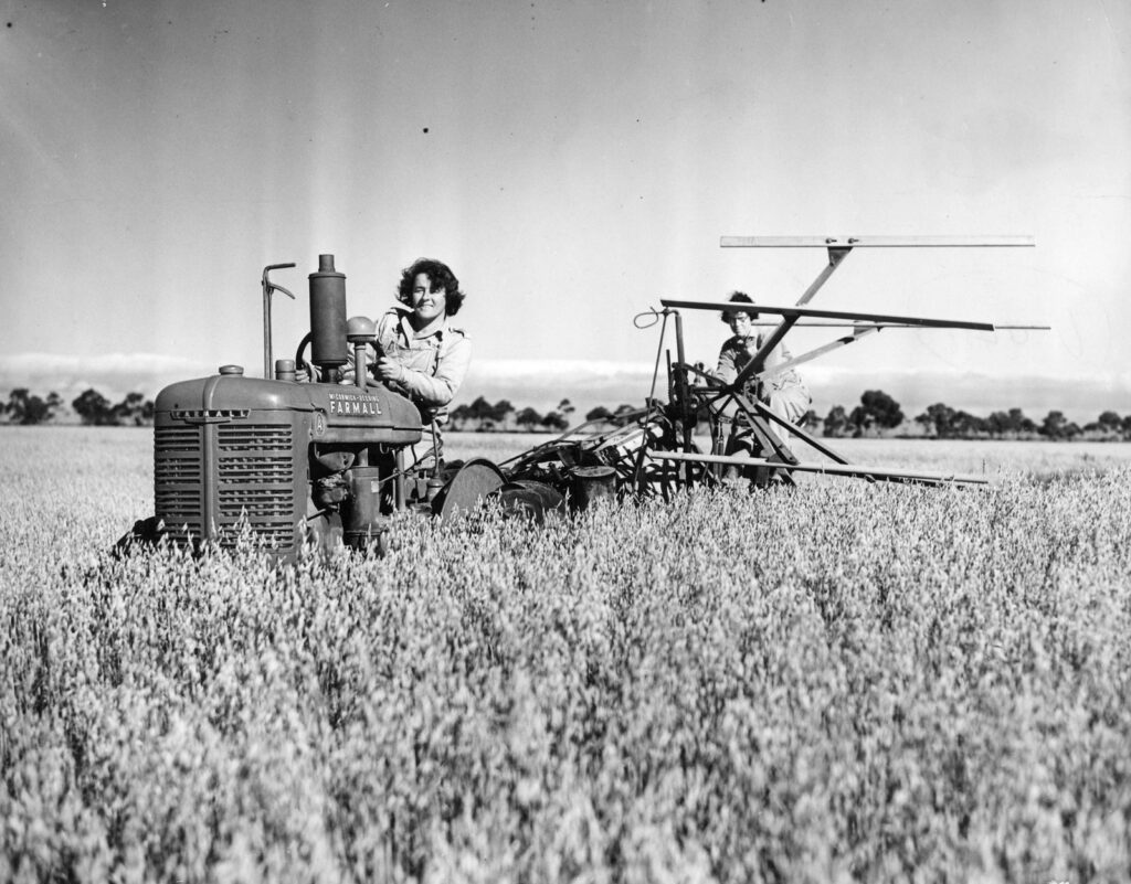 Black and white image of women operating a harvester in a field