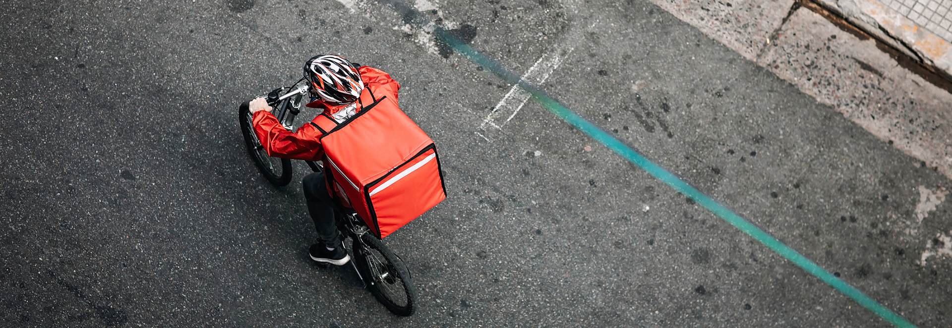 View from above of a young man working for a food delivery service, riding bike
