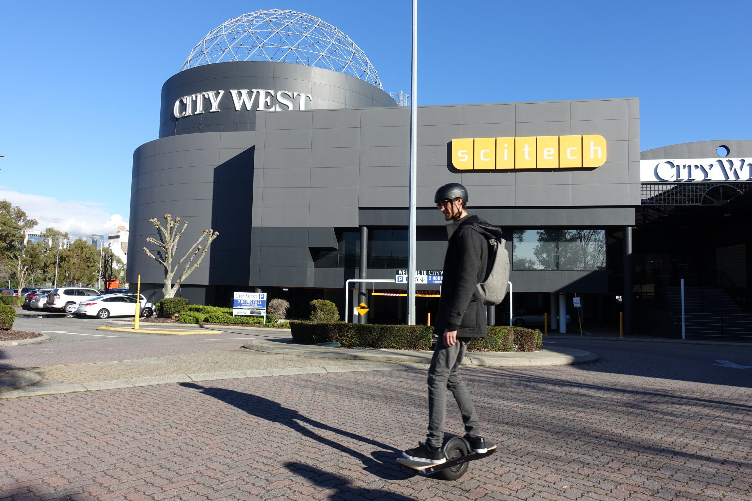 Sam rides Onewheel through a carpark outside Scitech in West Perth