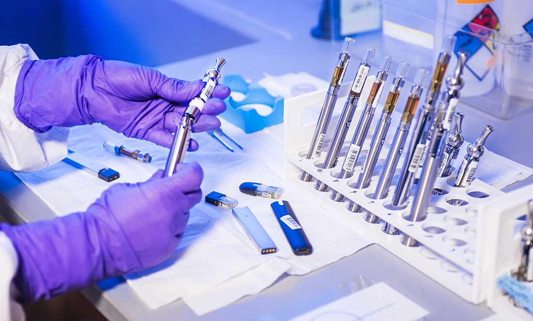 gloved hands of a laboratory technician working with electronic cigarettes