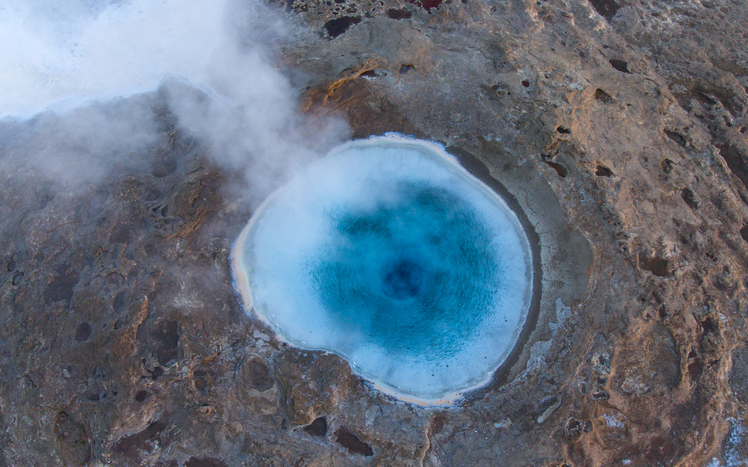 A geyser - this one's in Iceland - seen from above. It's a circular patch of water, crusty round the edges, and it does look kinda like a petri dish.