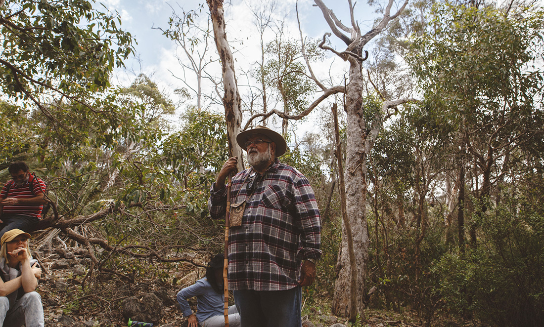 Dr Noel Nannup telling the story of 'The Carers of Everything' underneath tall native trees