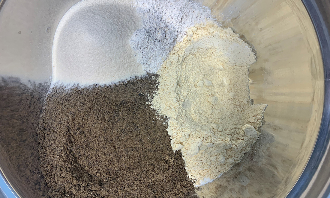 Three types of raw fish feed materials (that look like white, cream and brown powders) being blended together
