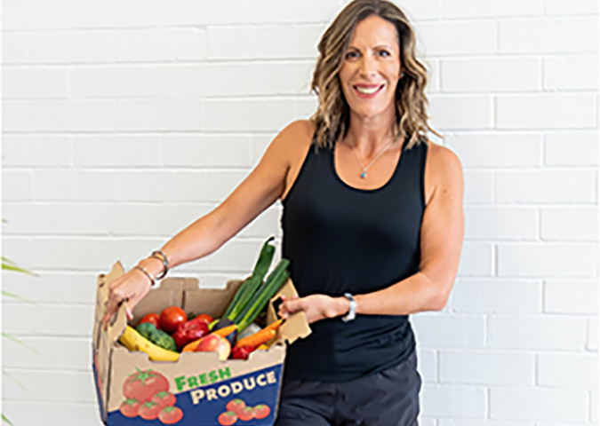 Life coach Sarah Rusbatch holding a produce box of fresh vegetables