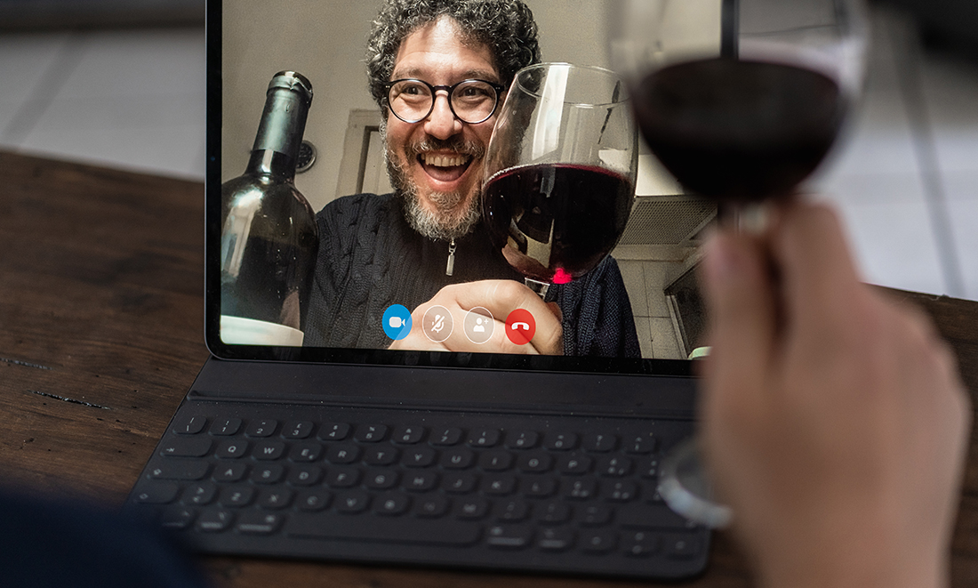 Two middle aged friends toasting with red wine in video calling