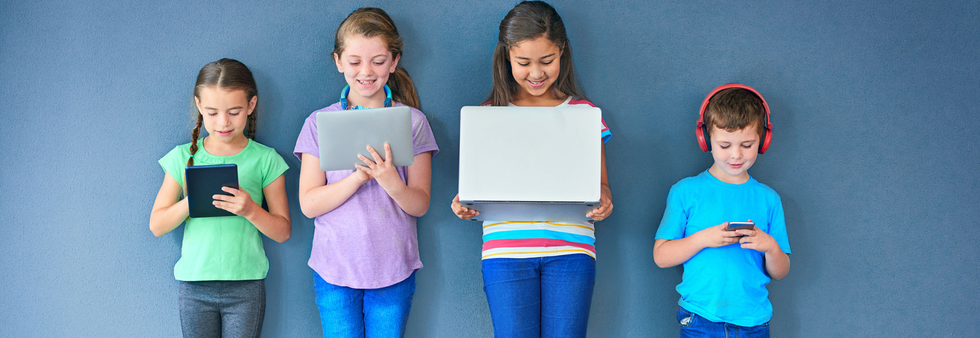 Studio shot of a group of kids using wireless technology against a blue background