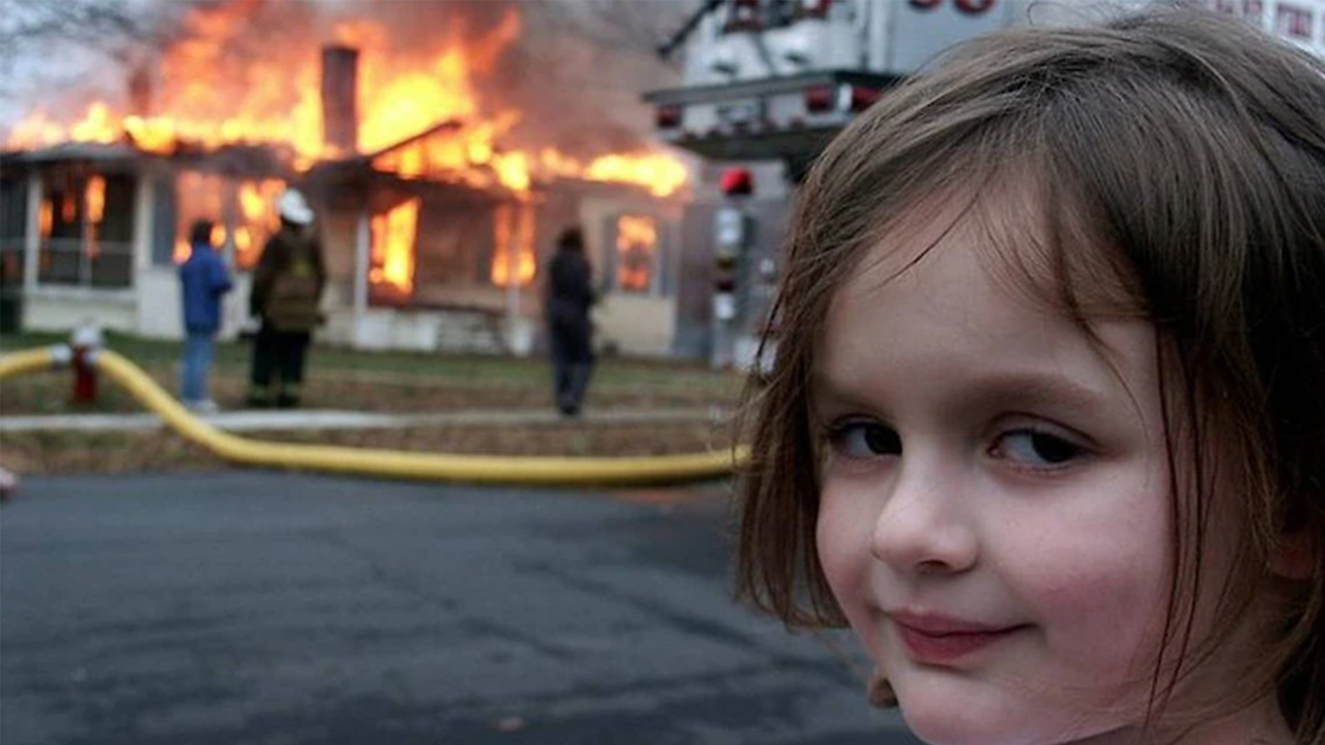 young girl smirking at camera while house burns in background