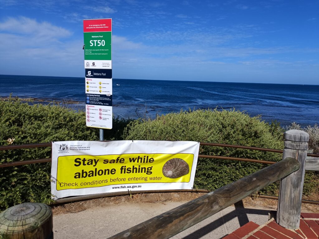 A banner at the entrance to the beach advises "Stay safe while abalone fishing"