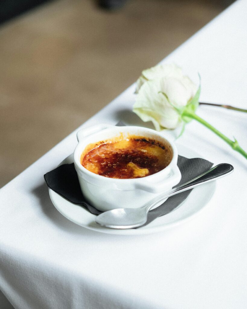 A photo of a creme brulee on a white plate, on a white tablecloth